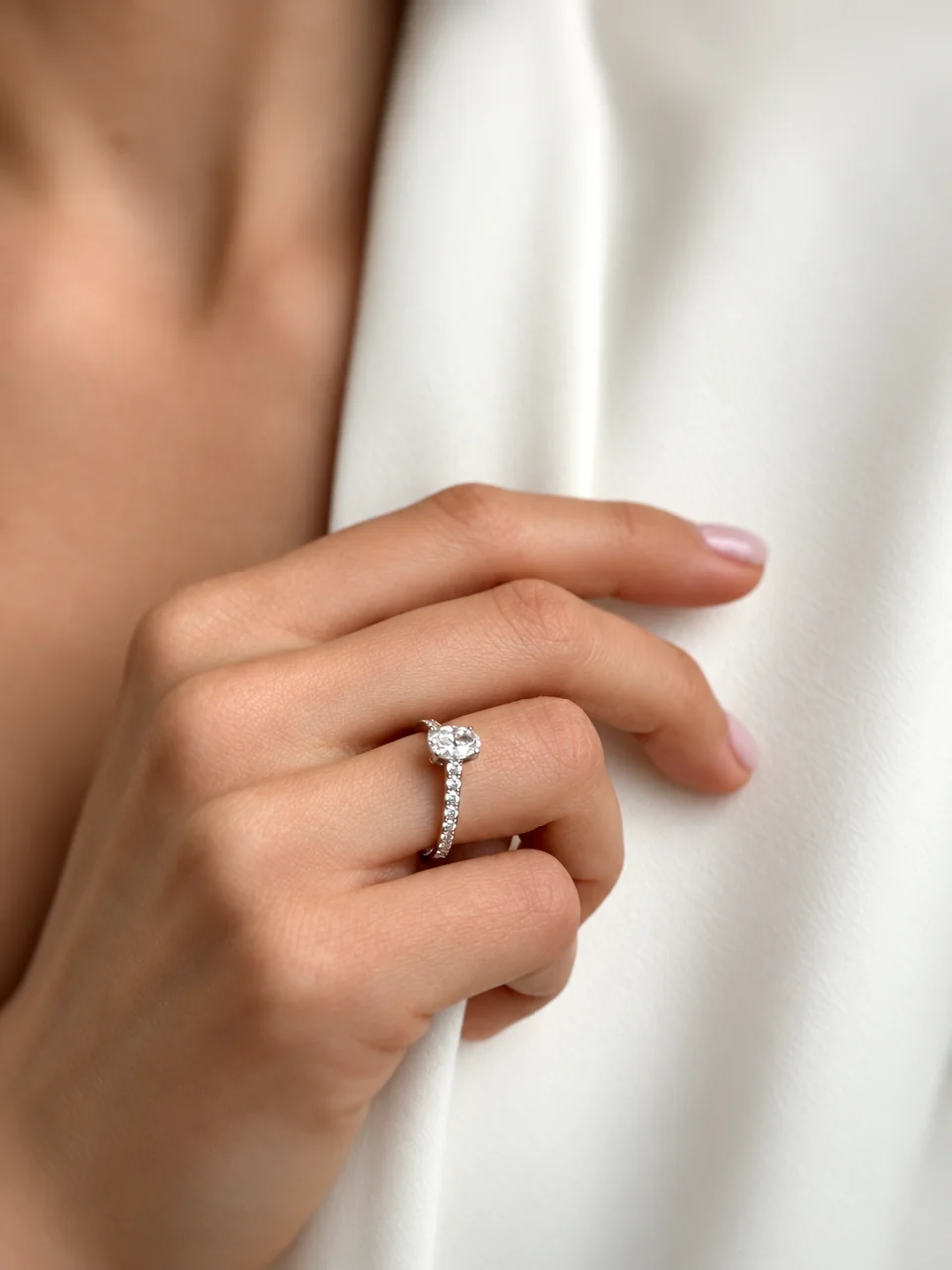 Close-up of a hand wearing a ring against a white jacket