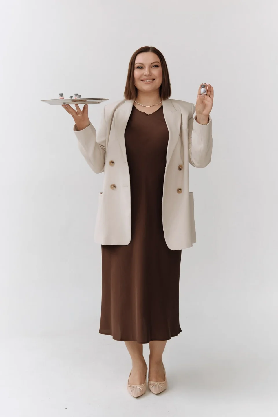 Studio portrait of a professional holding a tray and a small product
