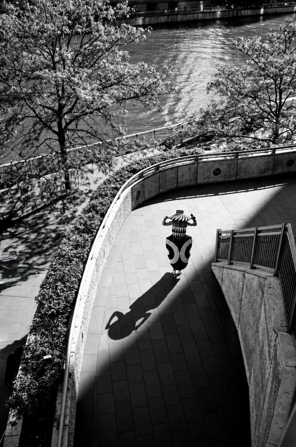 Overhead black-and-white fashion photograph along a riverside walkway
