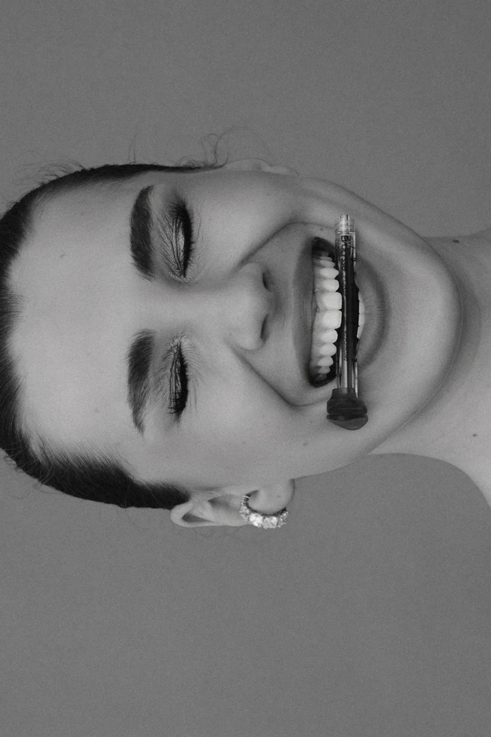Playful black-and-white beauty portrait with a lip applicator