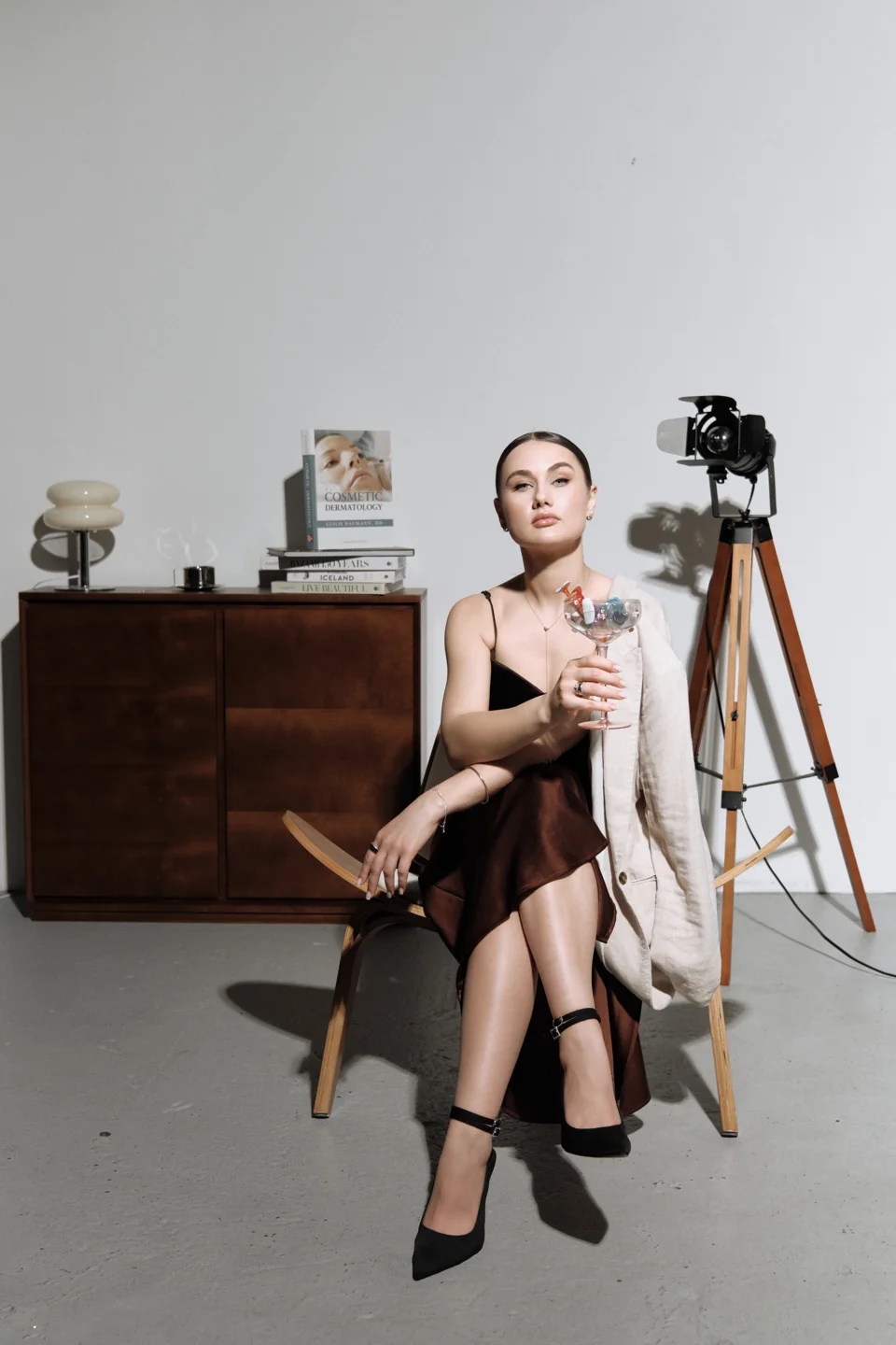 Seated fashion portrait in a studio beside a vintage camera