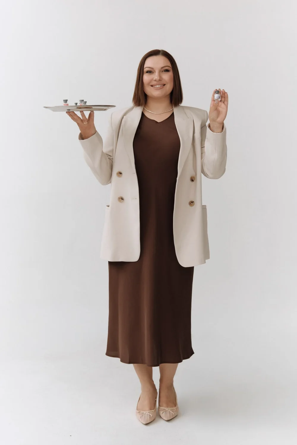 Full-length portrait of a woman holding a tray and a small vial