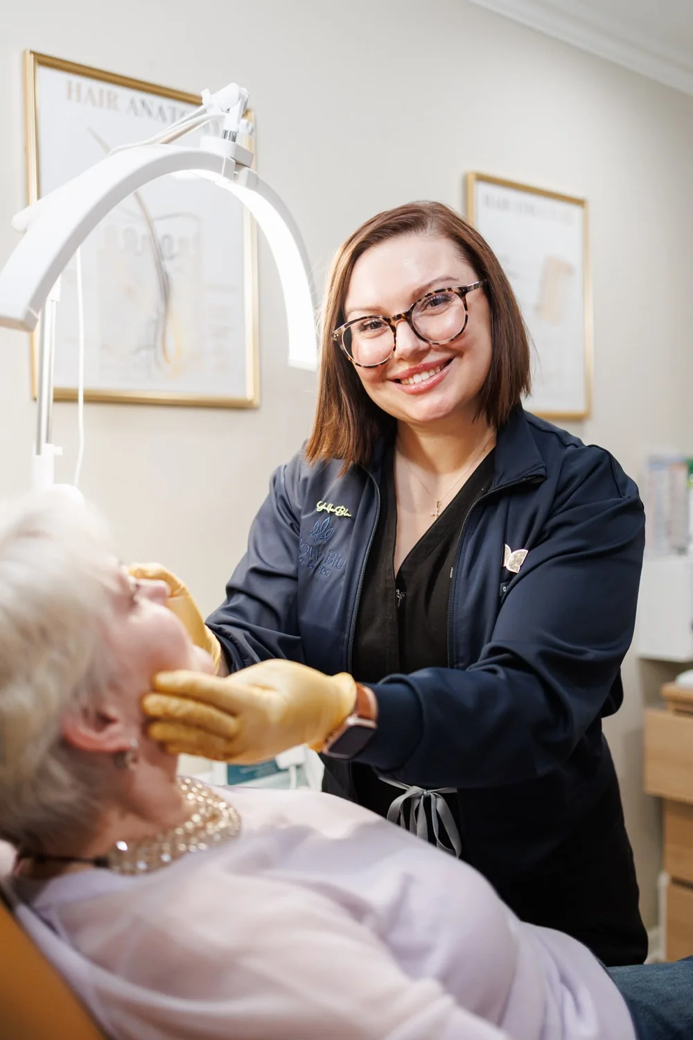 A smiling woman wearing glasses beside a reclining client